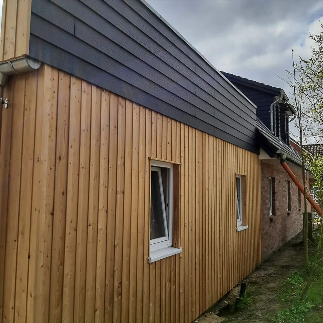 mit hellem Holz verkleidete Fassade, mit dunkelgrauem Abschluss